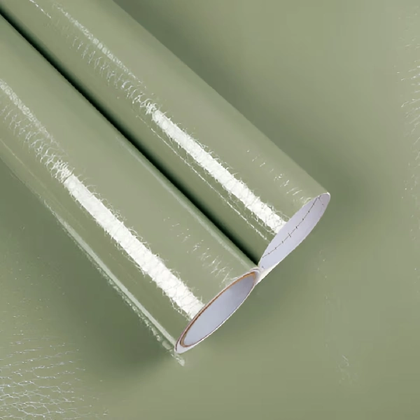 A roll of glossy solid color vinyl wrap in a light green or sage hue.