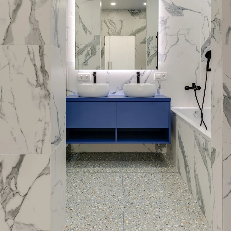 Bathroom with a blue floating vanity and a white marble vinyl wrap on the walls.