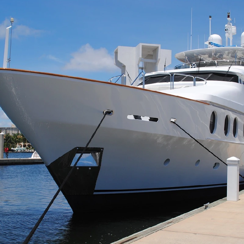 Bow of a large white yacht with a black vinyl wrap on the lower hull.