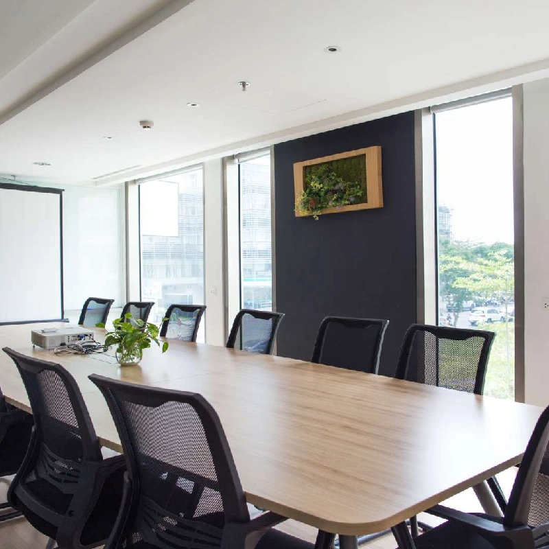 Conference room with a wooden table, chairs, and a framed plant display on the wall.