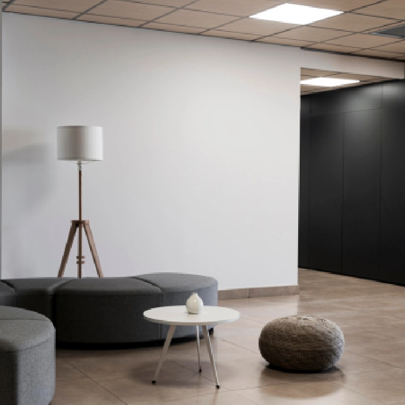 Contemporary office waiting area with a lamp, small table, and seating.