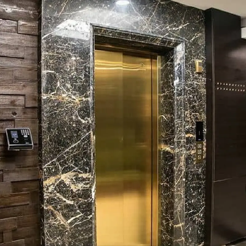 Elegant brass elevator doors surrounded by a black marble vinyl wrap.