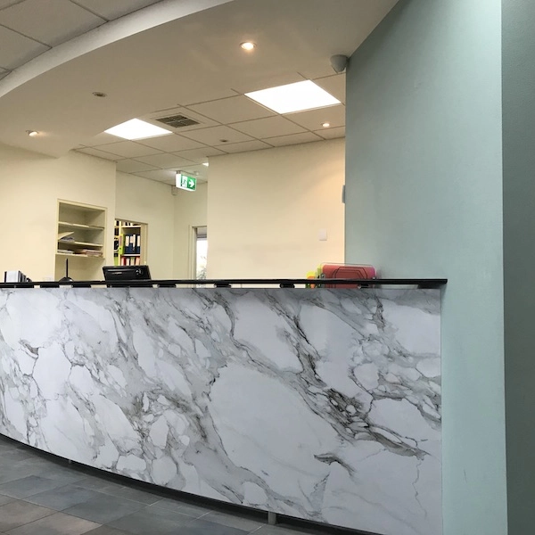 Office reception desk with a white marble-look finish.