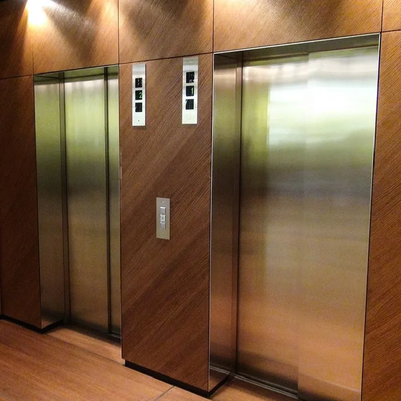 The inside of an elevator with woodgrain vinyl wrap and stainless steel walls.