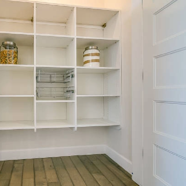 Walk-in pantry with white shelves and a few storage jars.