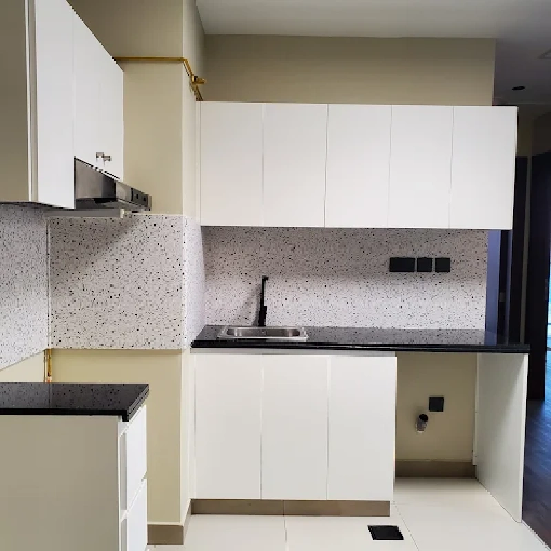 White kitchen cabinets with a black and white flecked vinyl wrap backsplash