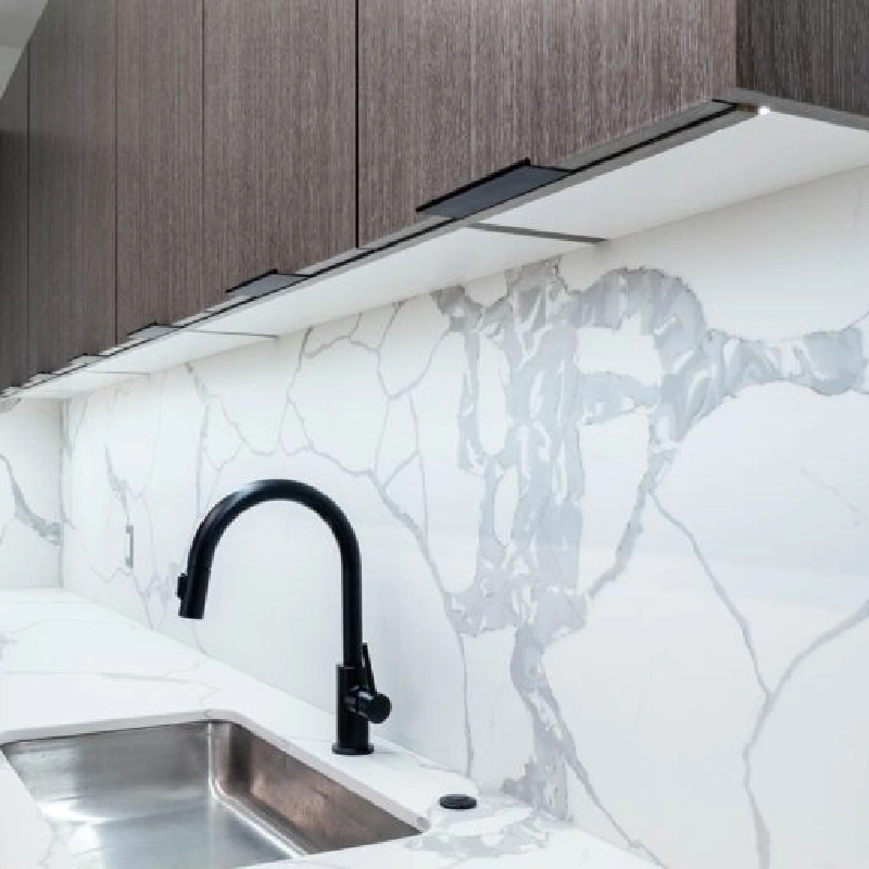 White marble-patterned vinyl wrap with large grey veins on a kitchen backsplash.