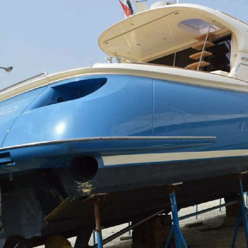 blue yacht with a vinyl wrap, showing a small port and a white stripe