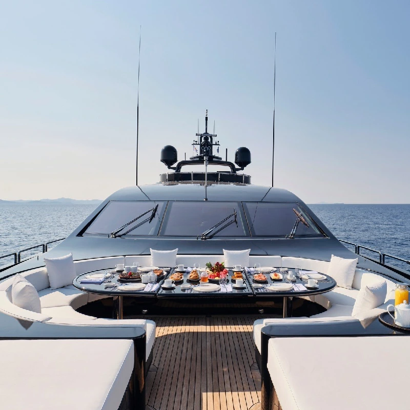 deck of a yacht vinyl wrap with a dining table set for a meal, a clear blue sky, and the ocean