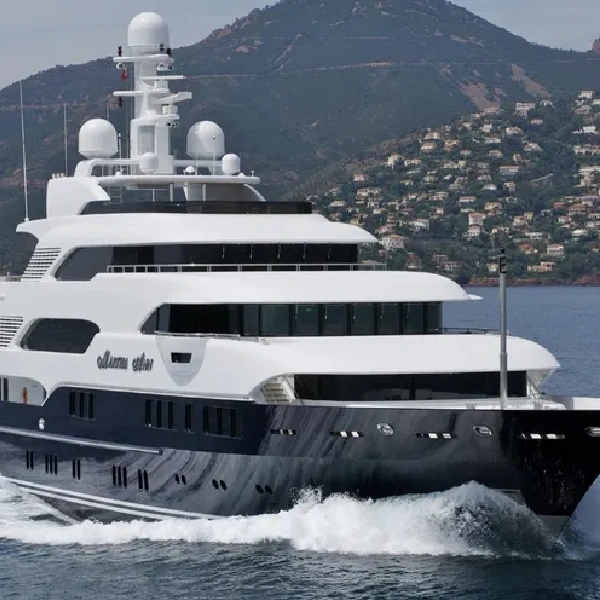 luxurious yacht with a dark blue vinyl wrap on its hull is seen from the side, moving through the water