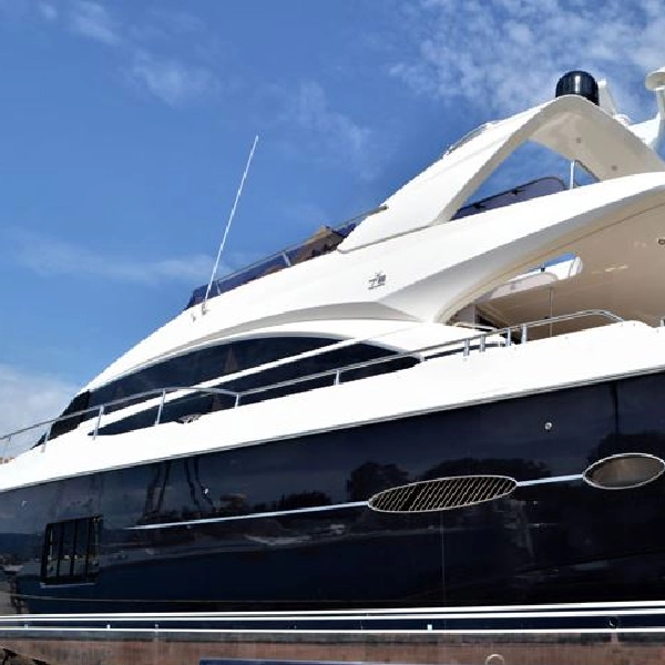 luxurious yacht with a dark blue vinyl wrap on its hull, set against a bright blue sky