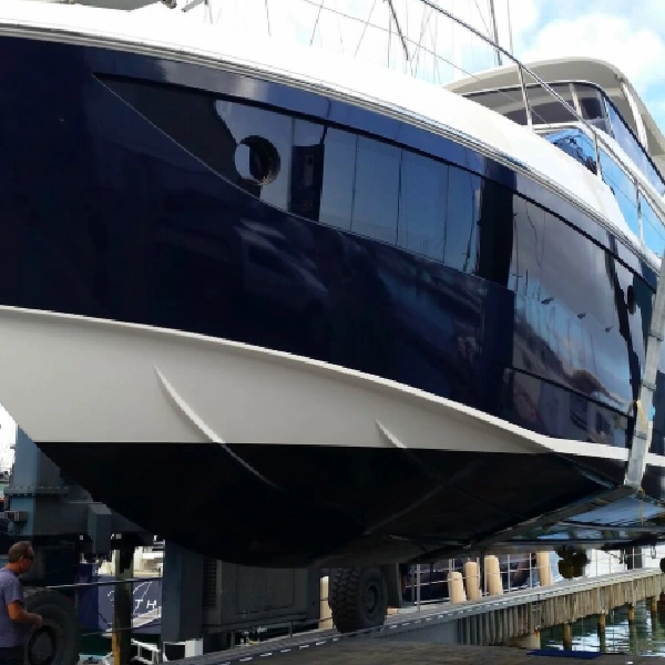 yacht on a lift with a dark blue antifouling vinyl wrap on the hull and a white wrap