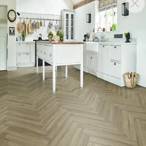 Light-colored wood-look flooring laid in a herringbone pattern in a white