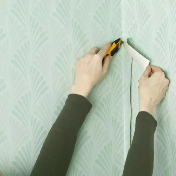 trimming patterned wallpaper with a utility knife to create a smooth seam