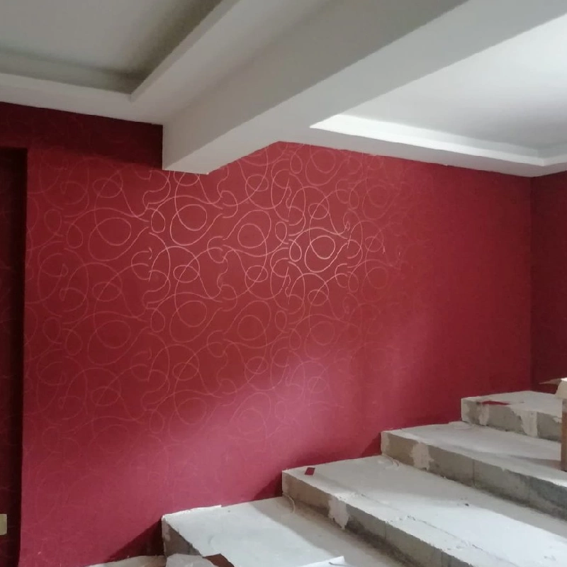 wall covered in red wallpaper with a swirling, abstract pattern in gold lines.